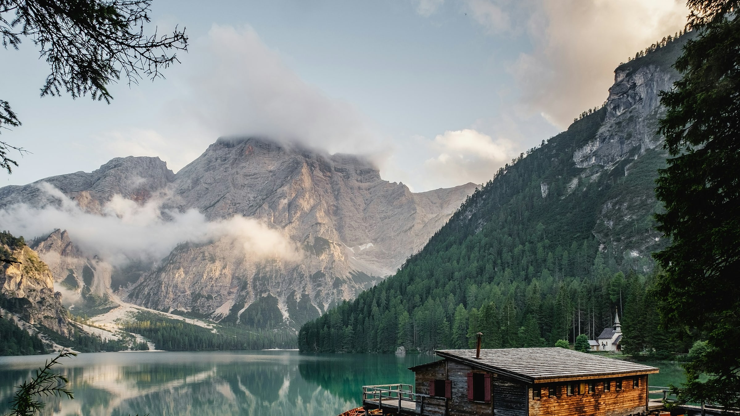 An alpine lake and boathouse beneath clouded peaks