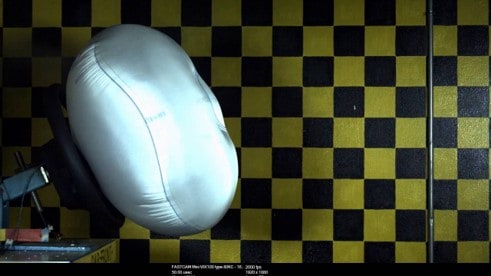 Airbag mid-deployment against checkered test background