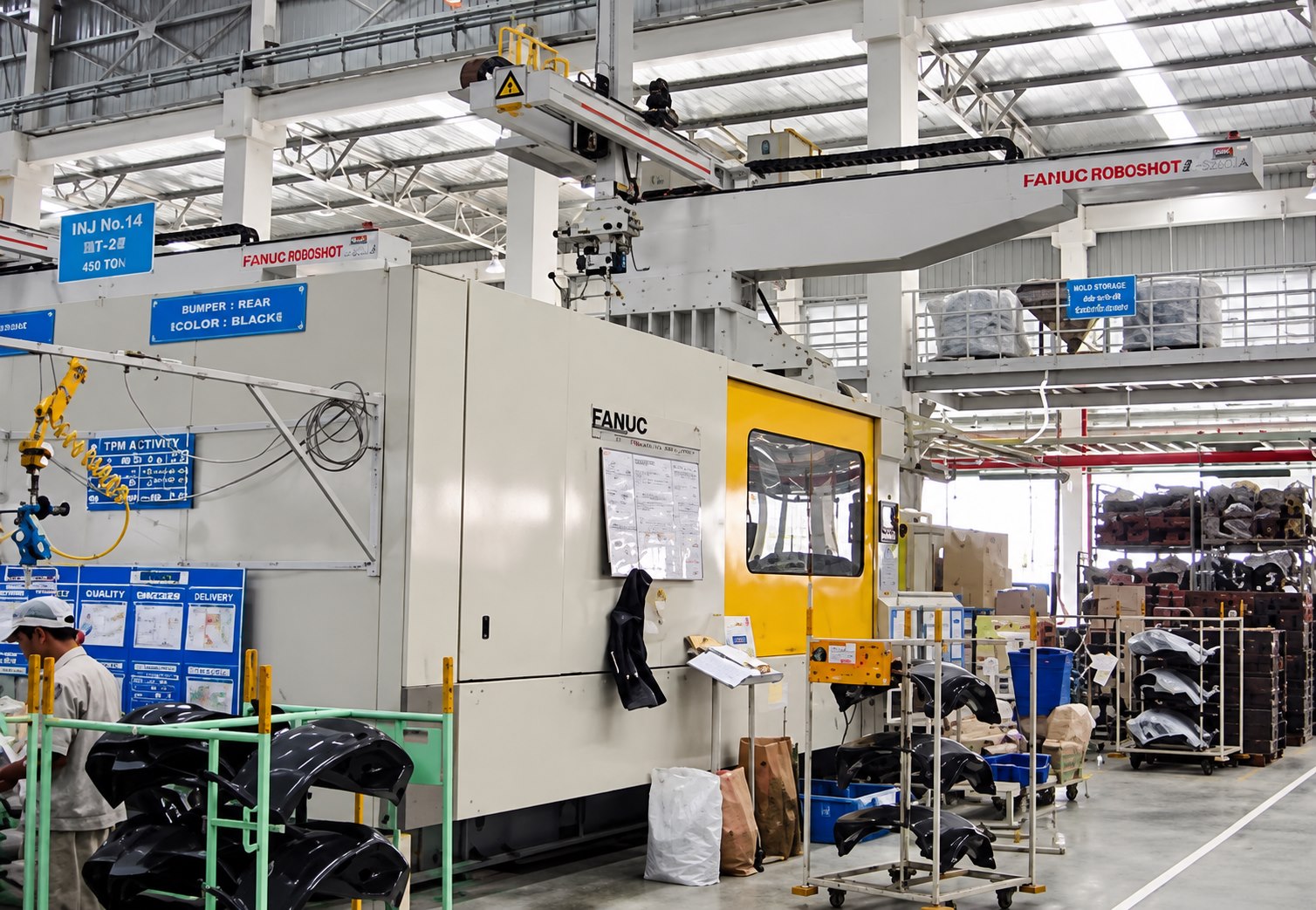 Large-tonnage injection moulding cell with robotic take-out and finished interior trim on racks
